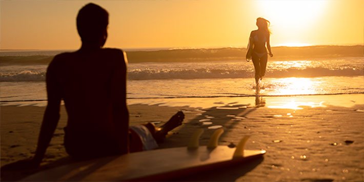 Grupo de pessoas surfando no pôr do sol em praia no Rio de Janeiro