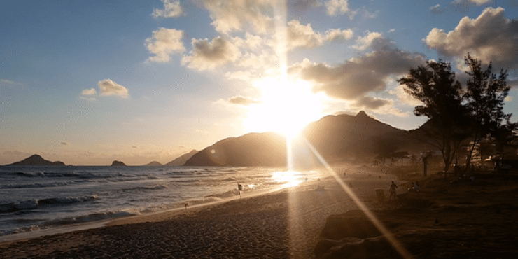 : O Sol se põe em meio aos morros que ficam à direita da Praia da Macumba, um dos lugares preferidos dos surfistas, que aparece com poucos banhistas curtindo o fim de tarde. 